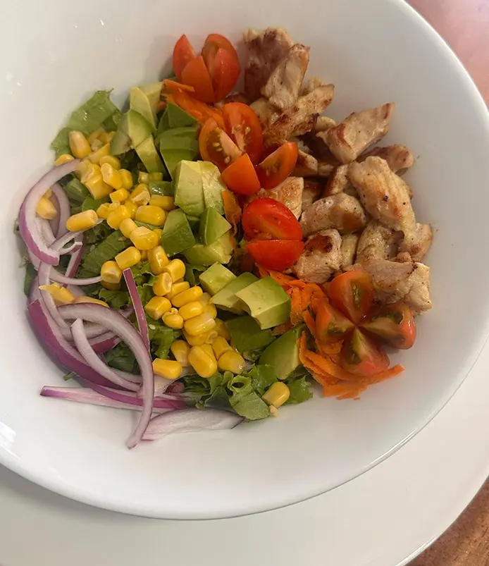 Ensalada de pollo con maíz dulce, tomate cherry, cebolla morada y aguacate
