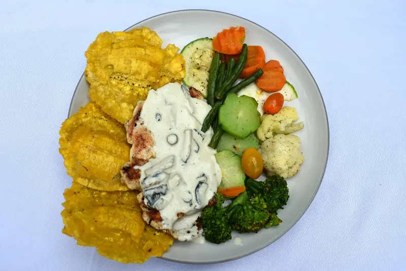 Pescado en salsa blanca con patacones y vegetales